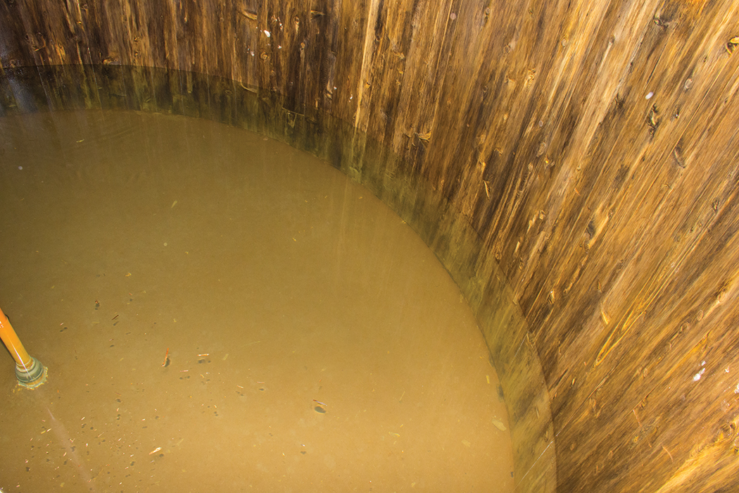 The undisturbed sediment at the bottom of a newly drained water tank coats the bottom of the tank in a layer of muck that can be a breeding ground for potential pathogens.