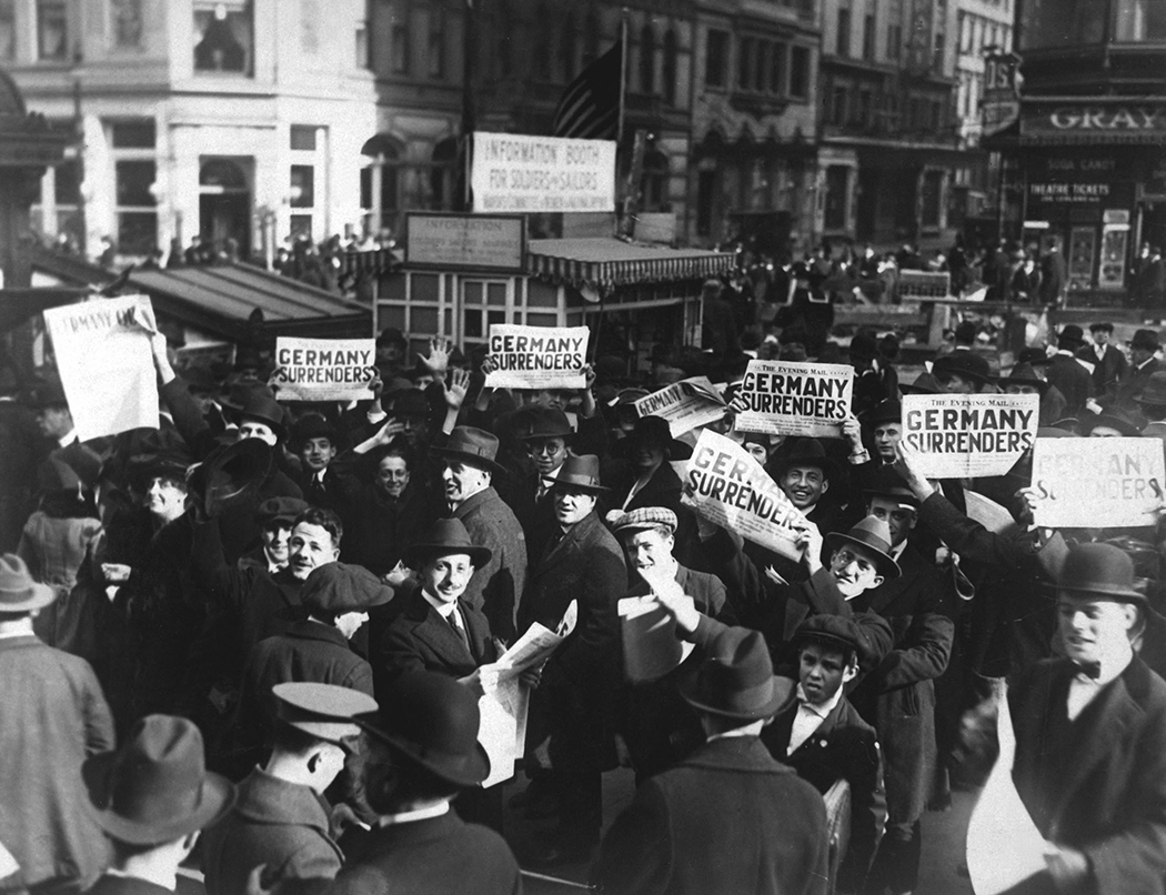 A crowd at Times Square holding up headlines reading 'Germany Surrenders,' on November 7, 1918. Four days later, on Nov. 11. 1918, the headlines would be correct when an armistice ended WWI.