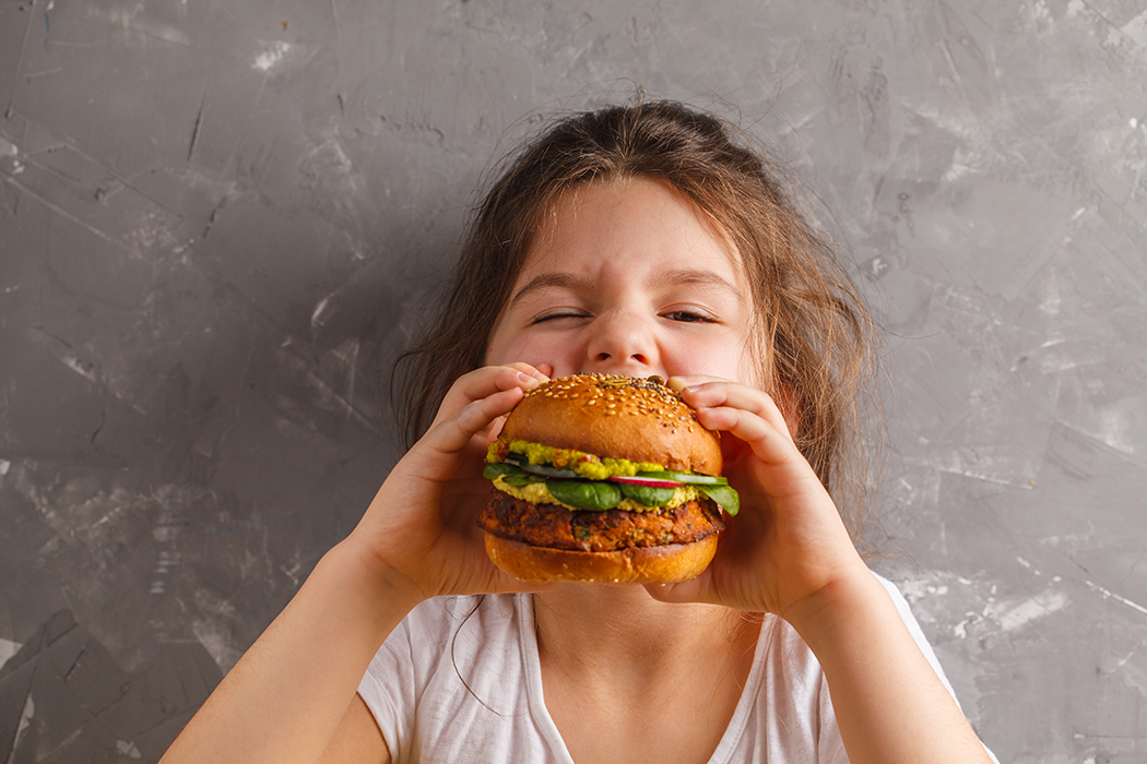 Little girl eating a veggie burger Little girl eating a veggie burger