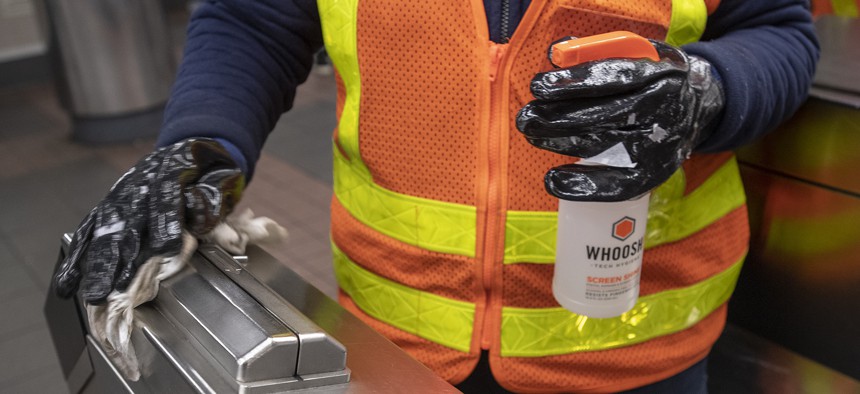 An MTA worker sanitizing the card reader. 