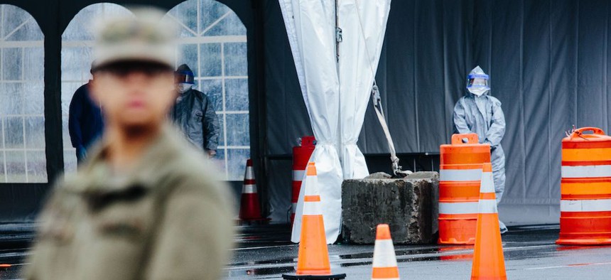 Medical professionals in protective suits wait to take information from people at the drive-through COVID-19 mobile testing center in New Rochelle, New York on March 13, 2020.