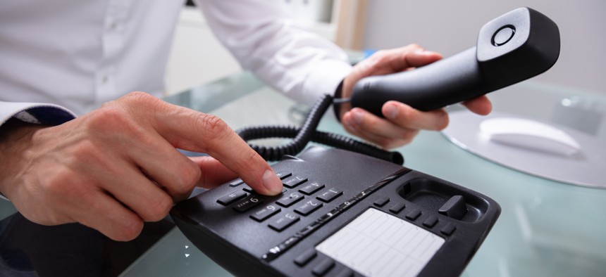 A man dialing a number on a telephone.