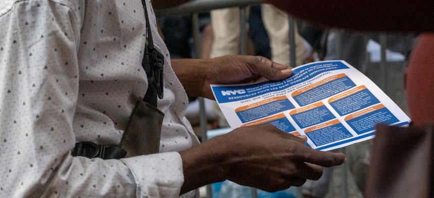 Migrants outside the Roosevelt Hotel were provided city resource sheets.