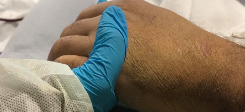 Jacob Gris holds his father Juan Francisco Hidalgo Flores's hand on the day of his death, Nov. 16, 2017.