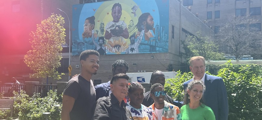 Dante de Blasio (in the back row, on the far left) and his father Bill de Blasio (also back row, far right) with artist Layqa Nuna Yawar, front row far left, pose with community members at the unveiling of “Colors of My City” at Vital Brookdale supportive housing complex in Brownsville, Brooklyn, on Friday.